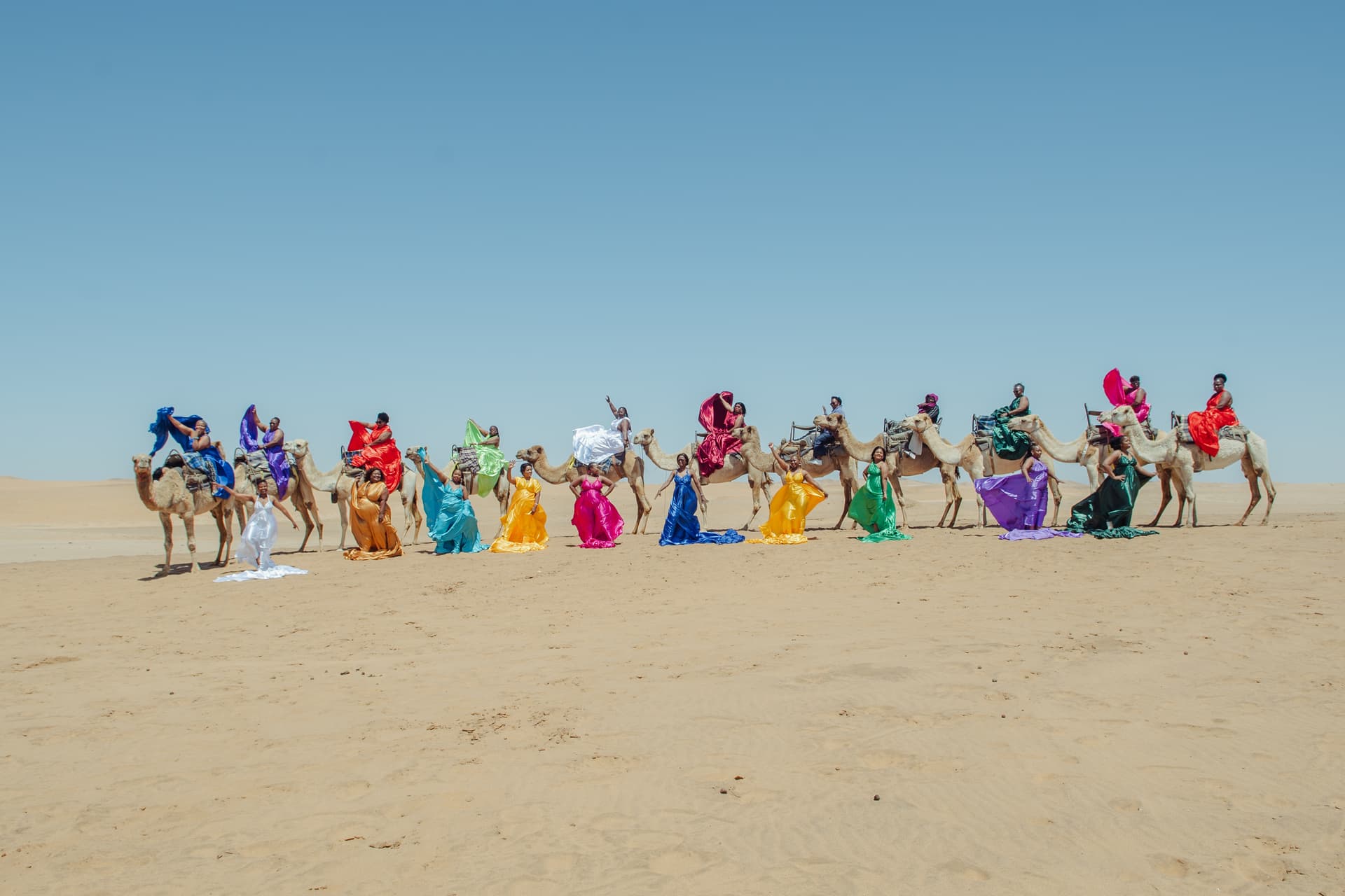 Black Basket Travel guests riding camels across Namibia's desert dunes